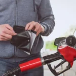 Lack of money for gasoline and fuel. Expensive gasoline. Driver man holds one dollar end empty wallet against the background of a fuel nozzle in the gas tank. increase in gasoline prices concept.