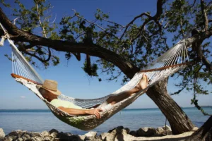 Senior man with hat on face sleeping in hammock, side view
