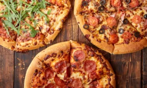 Composition of three various kinds pizzas on wooden table