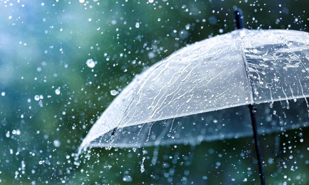 Transparent umbrella under rain against water drops splash background. Rainy weather concept.
