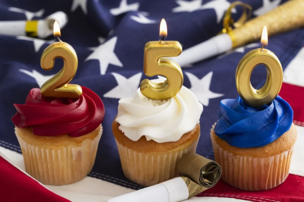 Celebration of America's 250th birthday with cupcakes and candles on a flag background