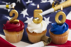 Celebration of America's 250th birthday with cupcakes and candles on a flag background