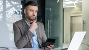 Businessman pondering over financial reports in modern office