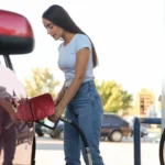 Young woman refueling car at self service gas station