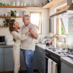 Couple, dance and kitchen with a senior woman and man dancing while happy together in their home. Retirement, smile and love with elderly pensioners being romantic in a house in the morning