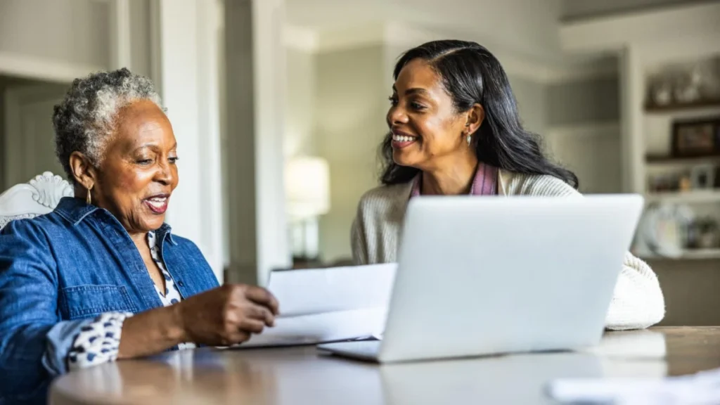 Adult daughter helping her senior mother look over bills at home