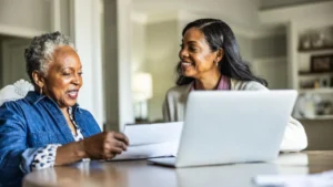 Adult daughter helping her senior mother look over bills at home