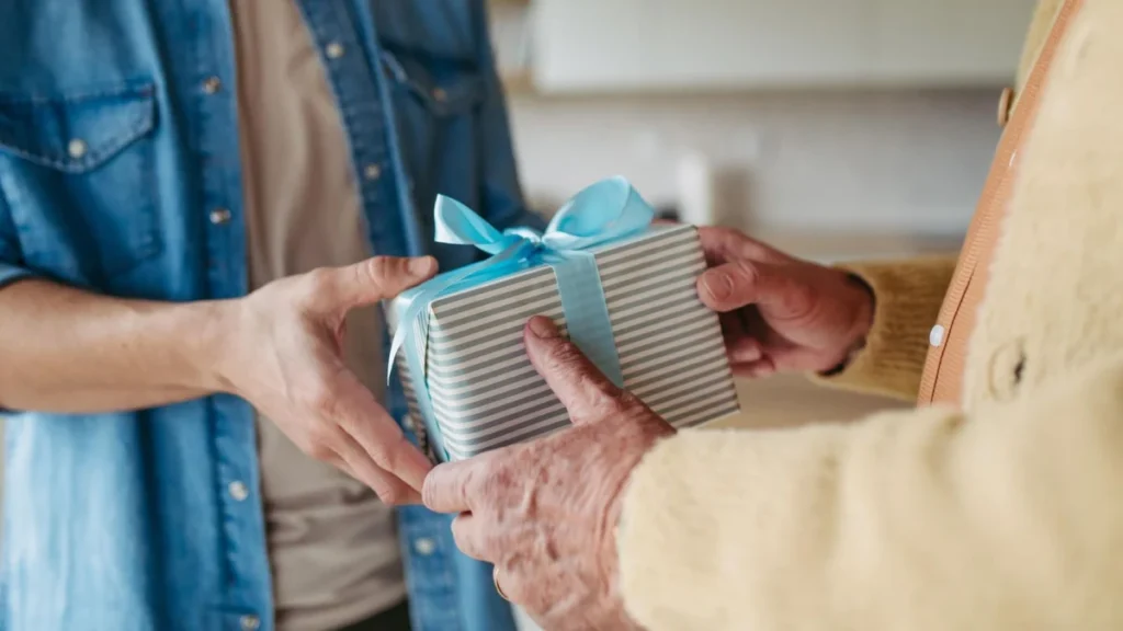 Close up of mature son bringing gift for Father’s day for his dad. Eternal love for parent and fatherly love.