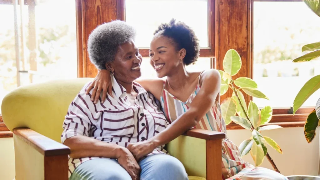 Senior woman and her daughter smiling at each other during a visit