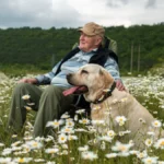The senior is resting in nature with his dog Labrador. Retirement walk. The concept of mental health.