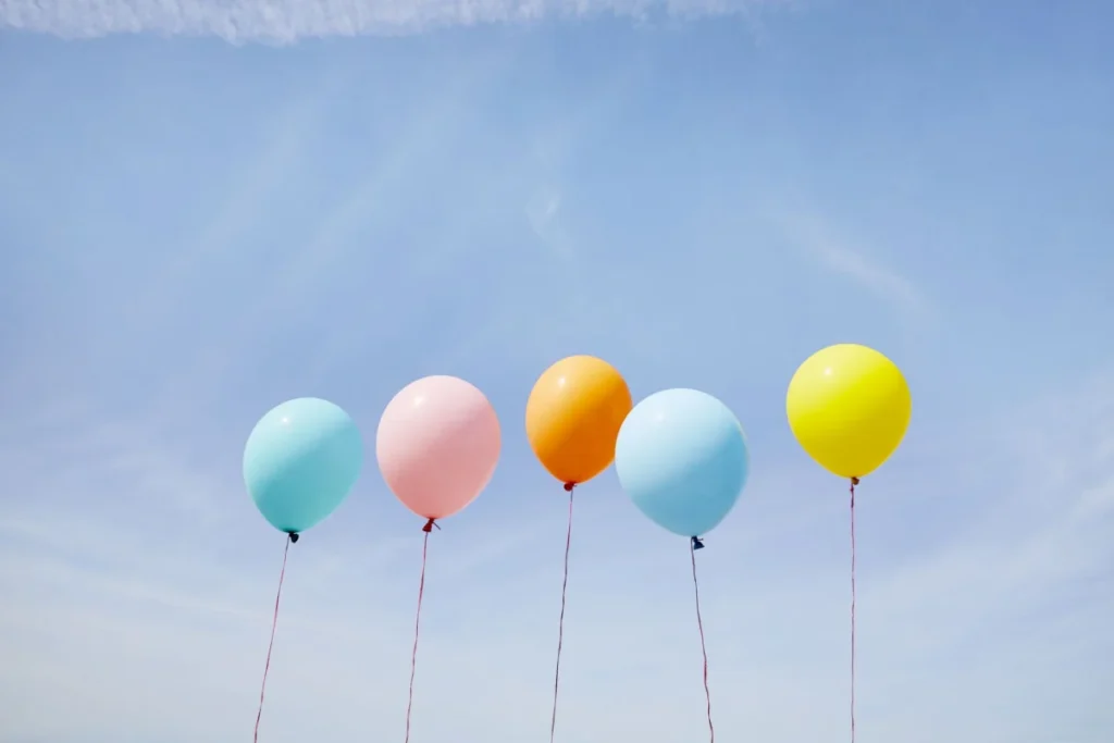 Five colorful balloons in a row against blue sky