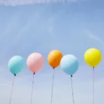 Five colorful balloons in a row against blue sky
