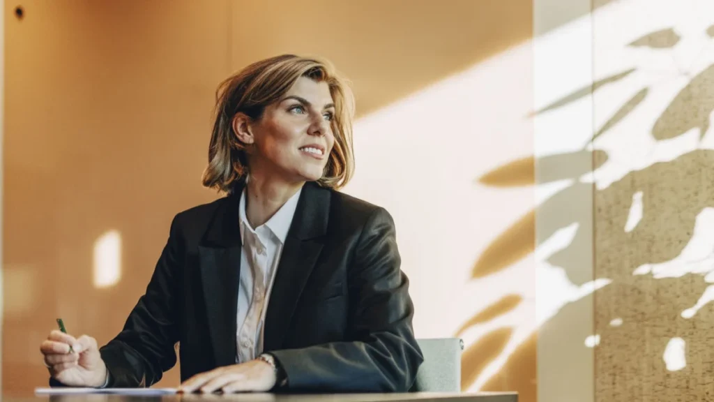 Low angle view of smiling female lawyer looking away while sitting at table in office board room